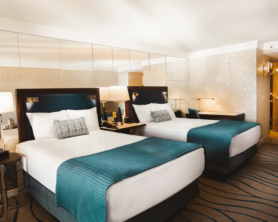 A resort guest room with two beds and teal linens.